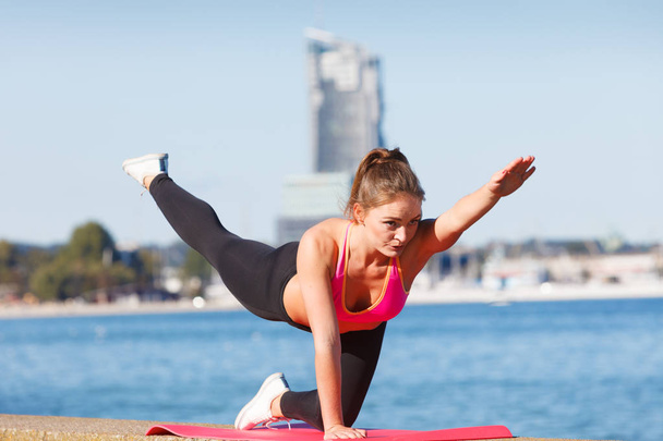 Woman doing sports exercises outdoors by seaside - Zdjęcie, obraz