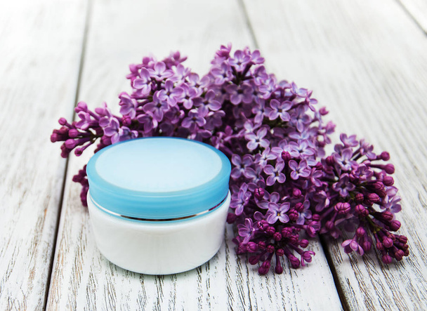 moisturizing cream and lilac flowers - Foto, afbeelding