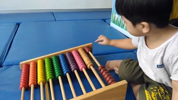 Niño jugando abacus grande feliz y divertido sobre fondo de plástico azul
, - Imágenes, Vídeo