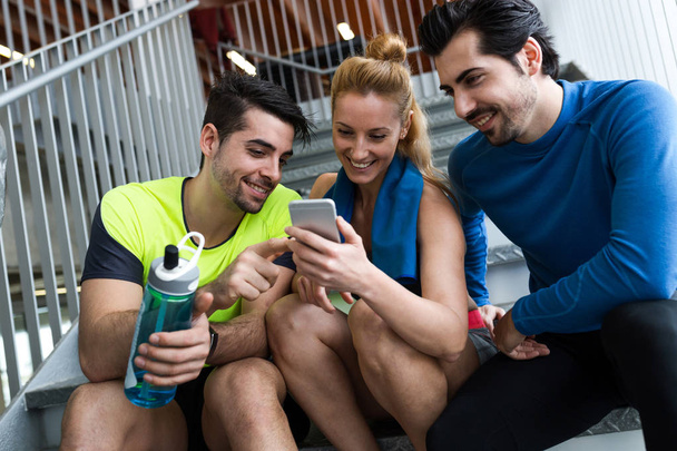 Ryhmä urheilullinen ihmiset käyttävät matkapuhelinta kuntosalilla
. - Valokuva, kuva