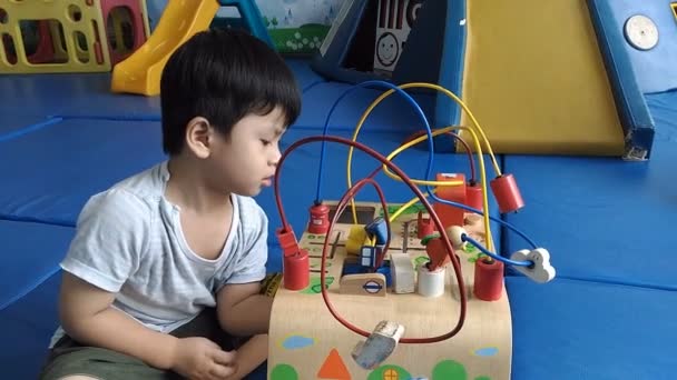 Kleiner Junge übt Gehirn mit Holzspielzeug auf dem Tisch, - Filmmaterial, Video