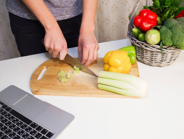 Чоловік готує салат, шукає рецепти онлайн за допомогою рук ноутбука крупним планом, кухонних інструментів та харчових інгредієнтів
 - Фото, зображення