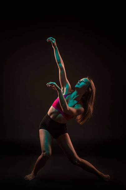 Young beautiful dancer in beige dress dancing on black background - Photo, Image