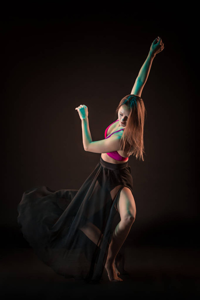 Young beautiful dancer in beige dress dancing on black background - Photo, image