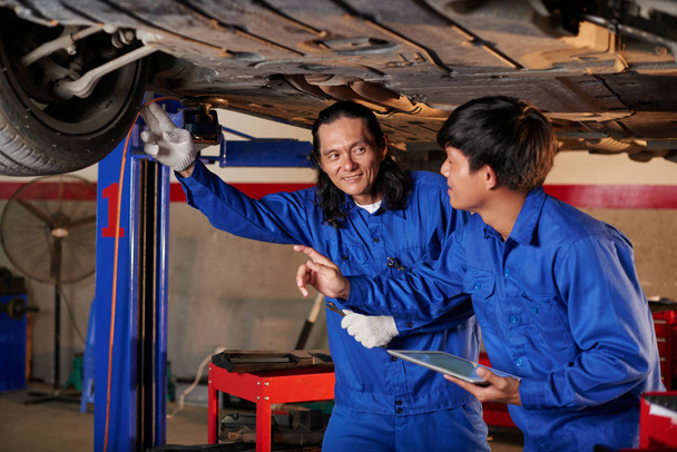 Erfahrener Mechaniker lehrt Mitarbeiter - Foto, Bild