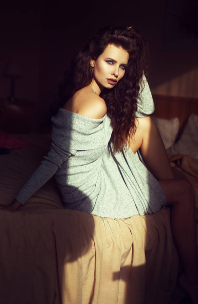 Sexy young fashion woman at hotel room, resting after shopping. Soft warm lights at window and in room.  - Photo, Image