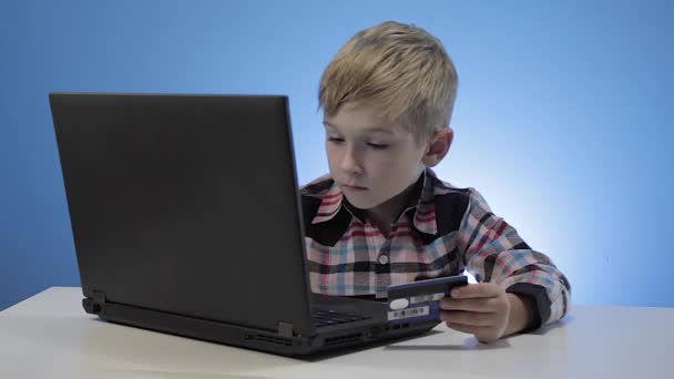 Ładny mały chłopiec za pomocą laptopa i karty kredytowej - Materiał filmowy, wideo
