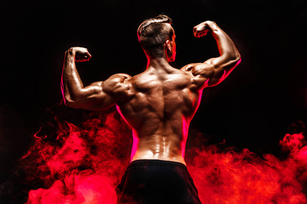 Back view of Unrecognizable man, strong muscles posing with arms up in smoke. - Foto, Imagem
