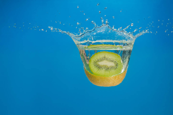 Kiwi splashing in water with blue background - 写真・画像