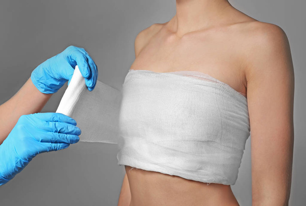 Doctor wrapping bandage around chest  - Foto, afbeelding