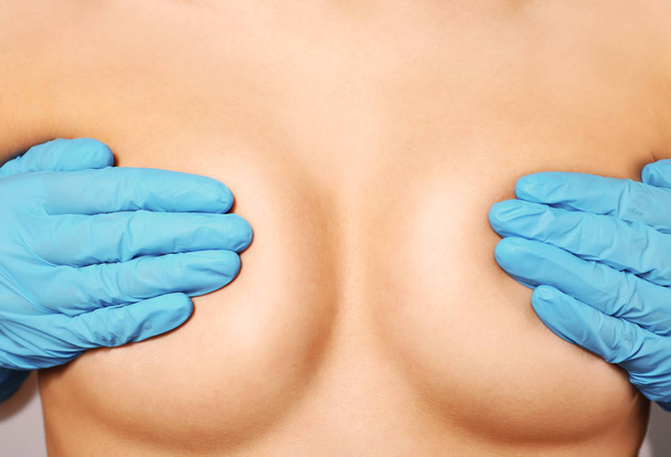 Female breasts covered with hands in rubber gloves, closeup - 写真・画像