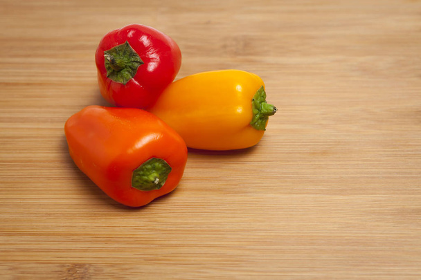 Sweet peppers on wooden cutting board - 写真・画像
