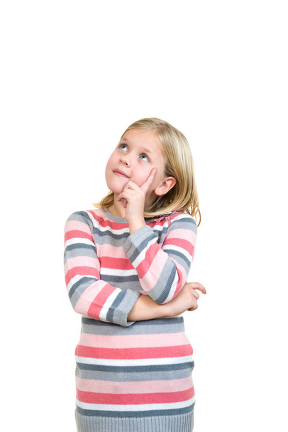 Cheerful little girl holding finger on chin and looking - Photo, Image