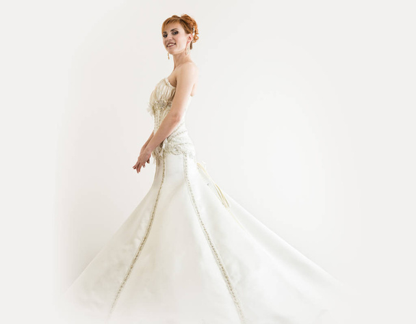 Beautiful young redhead bride wearing white wedding dress with professional make-up and hairstyle - Φωτογραφία, εικόνα