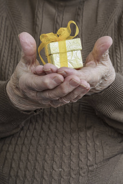Bir hediye holding kırışmış eller - Fotoğraf, Görsel