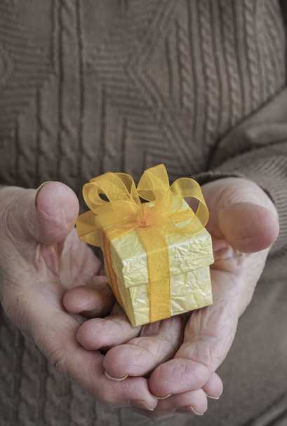 Bir hediye holding kırışmış eller - Fotoğraf, Görsel