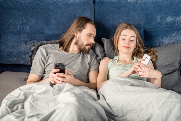 Пара в постели со смартфонами
 - Фото, изображение