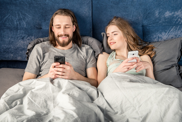 Paar mit Smartphones im Bett - Foto, Bild