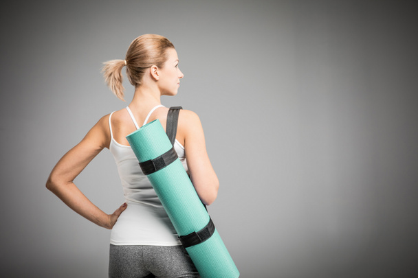 Sportlerin hält Yogamatte in der Hand   - Foto, Bild