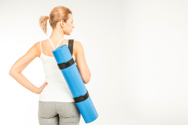 Sportswoman holding yoga mat   - Фото, изображение