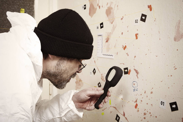 Police technician with loupe studying blood stains - Foto, Imagem