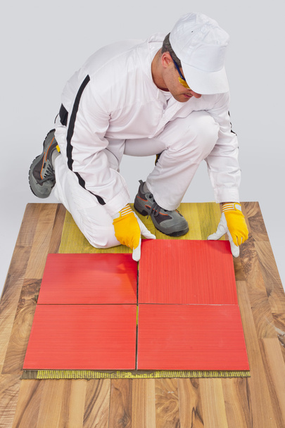 Travailleur applique des carreaux de céramique sur le sol en bois avec maille de fibre
 - Photo, image