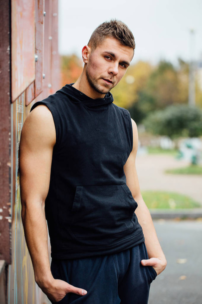 Portrait of a strong handsome man in training cloth. Posing in the hood. - Foto, afbeelding