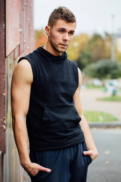 Portrait of a strong handsome man in training cloth. Posing in the hood. - Foto, imagen