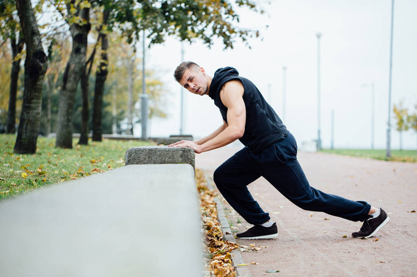 Male runner doing exercise, workout in the fall park. Push ups with bench. - Fotoğraf, Görsel