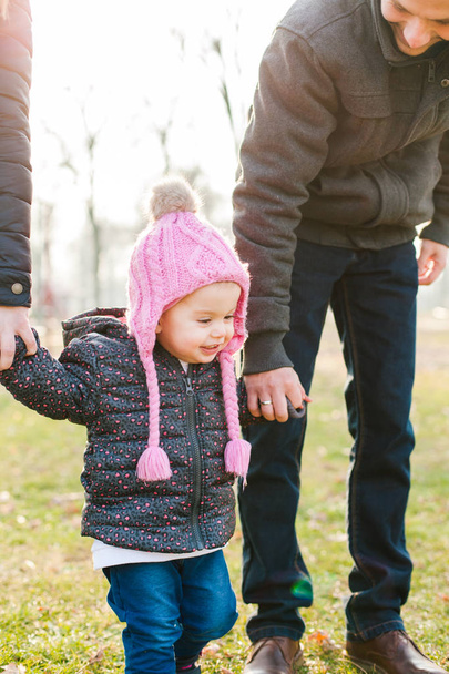 Happy child holding parents hands outdoor - Photo, Image