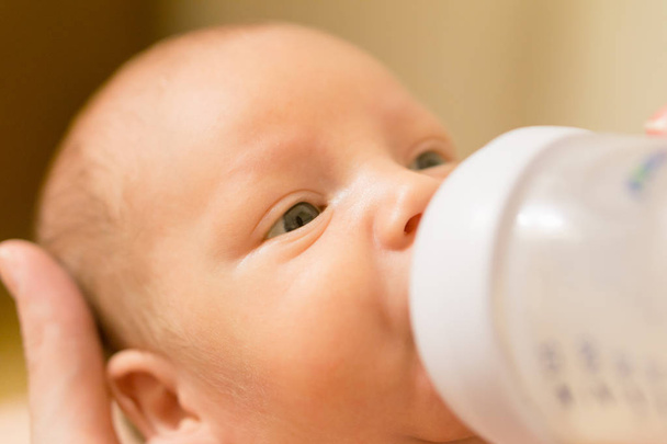 Lindo bebé recién nacido bebiendo leche de un biberón. Foto de stock
 - Foto, Imagen