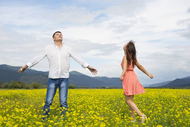 Lovers man and woman walk on the flower field. - Фото, зображення