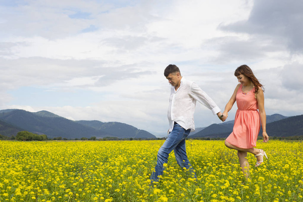 Lovers man and woman walk on the flower field. - Photo, image