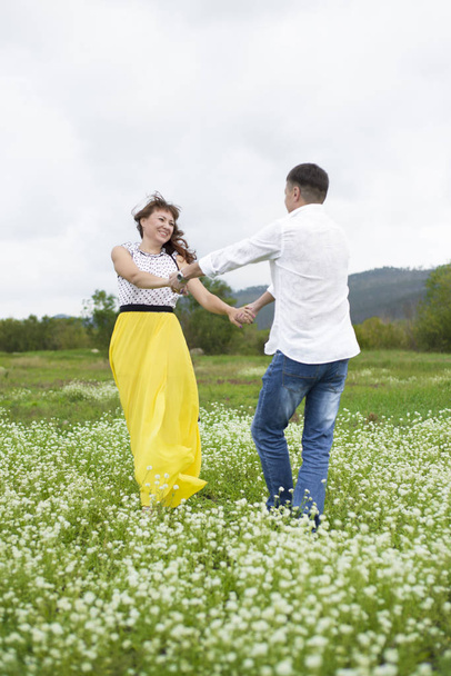 Lovers man and woman walk on the flower field. - Zdjęcie, obraz