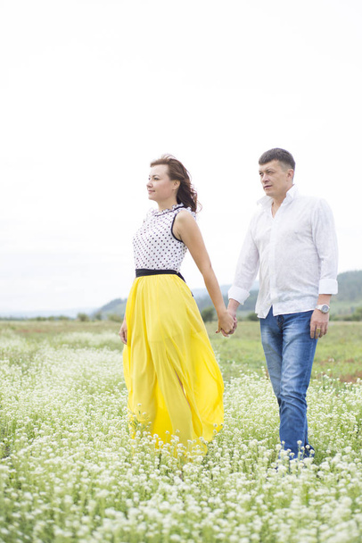 Lovers man and woman walk on the flower field. - Фото, зображення