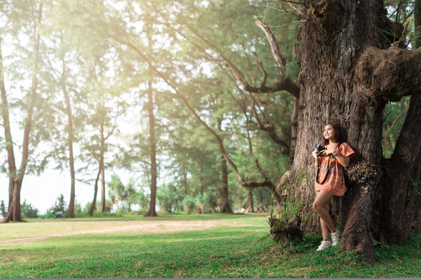 Beautiful girl leaning against tree in the morning. - Photo, Image