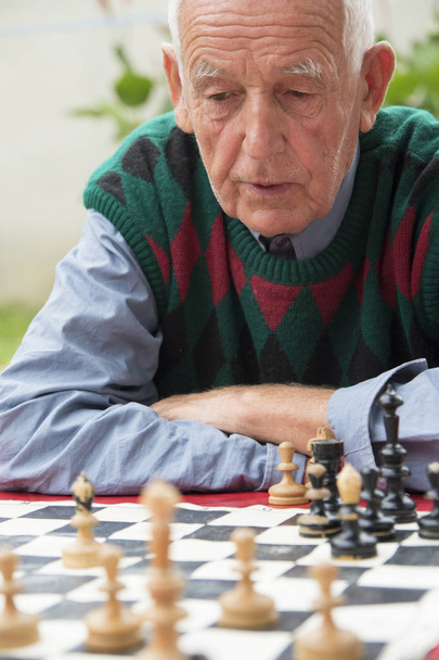 Old man playing chess - Foto, afbeelding