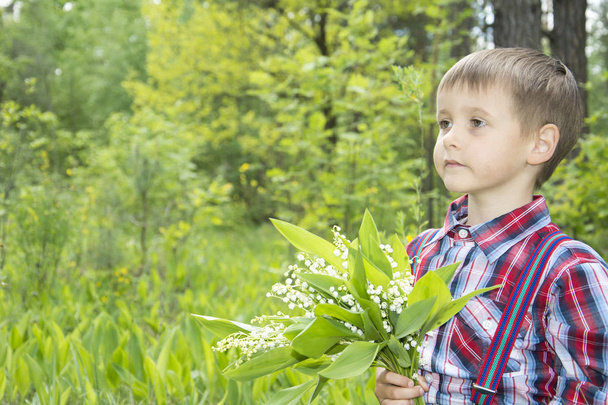 Spring in the forest little boy  holding a small bouquet lily of - Φωτογραφία, εικόνα