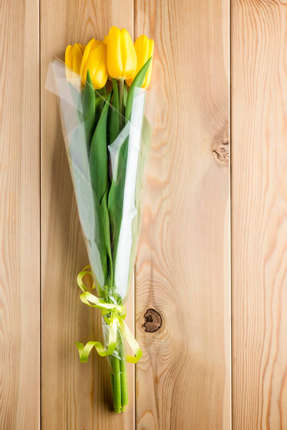 ein Strauß gelber Tulpen auf Holzbrettern in Nahaufnahme - Foto, Bild