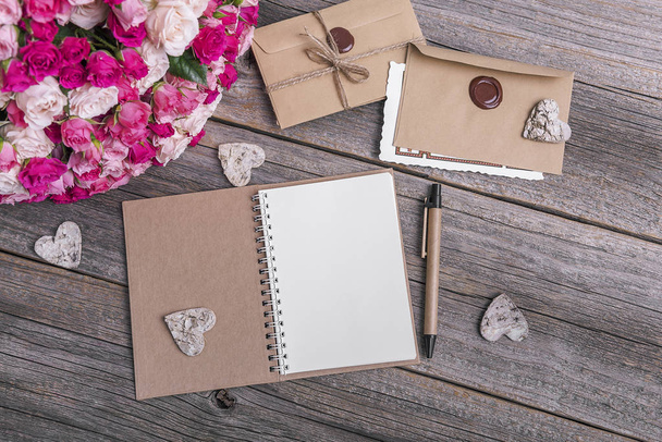 Notebook and roses on a wooden background. - Photo, Image