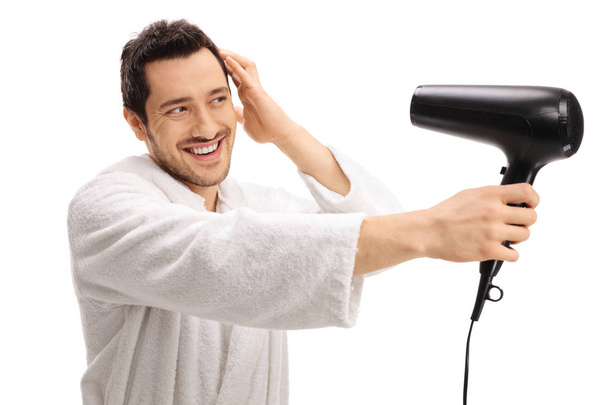 guy in a bathrobe drying his hair with a hairdryer - Фото, изображение