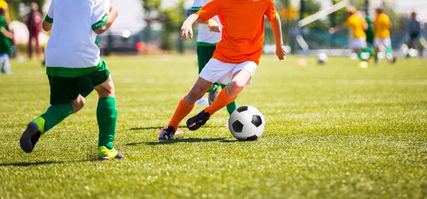 男の子はサッカー ボールを蹴るします。子供たちのサッカー チーム。子供のサッカーのピッチ上でボールで実行します。アクションの若いサッカー選手 - 写真・画像