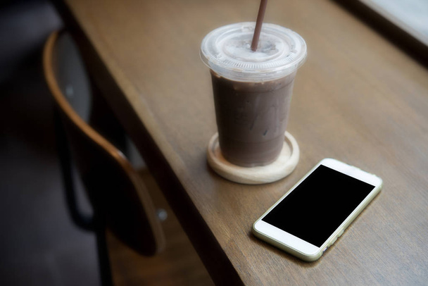 smart phone on the table with oce coffee inside coffee shop - Photo, Image