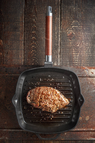Roast beef steak in spices on pan grill on the table - 写真・画像