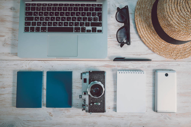 Top view of white surface with laptop, hat, eyeglasses, smartphone, camera - Valokuva, kuva
