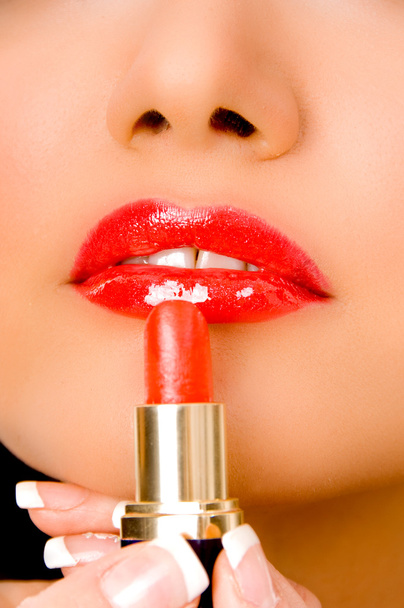 Close up of female applying lipstick - Foto, afbeelding