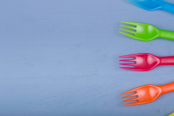 Garfos para crianças. Composição de garfos coloridos em uma mesa de madeira azul
 - Foto, Imagem