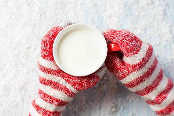 жіночі руки в рукавичках тримають гарячу чашку молока
 - Фото, зображення