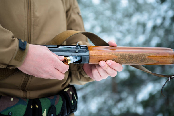 male hands hunter inserted cartridge 12 caliber rifle on a backg - Фото, зображення