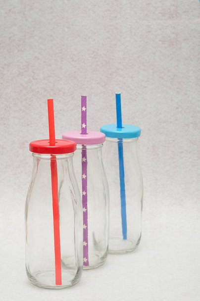 Três garrafas de vidro com palhas nas tampas
 - Foto, Imagem